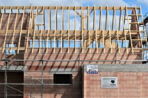 Building under construction with wooden roof trusses.
